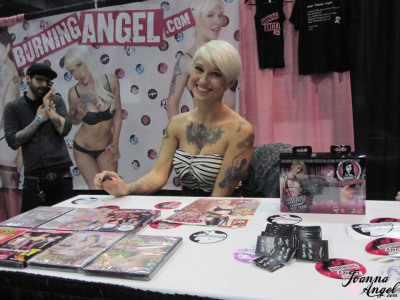 Tattooed alt models kiss and fool around during an XXX trade show