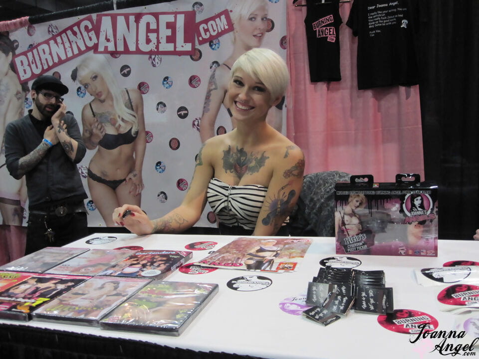 Tattooed alt models kiss and fool around during an XXX trade show page 1